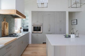 Une cuisine moderne avec des meubles gris, un plan de travail blanc et des appareils électroménagers en acier inoxydable.