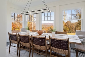 A dining area with a round table, six chairs, and a view of autumn foliage through large windows. - 8BR/13 bed Luxury Villa w/ Hot Tub (DT AVL 18min) (Fletcher)