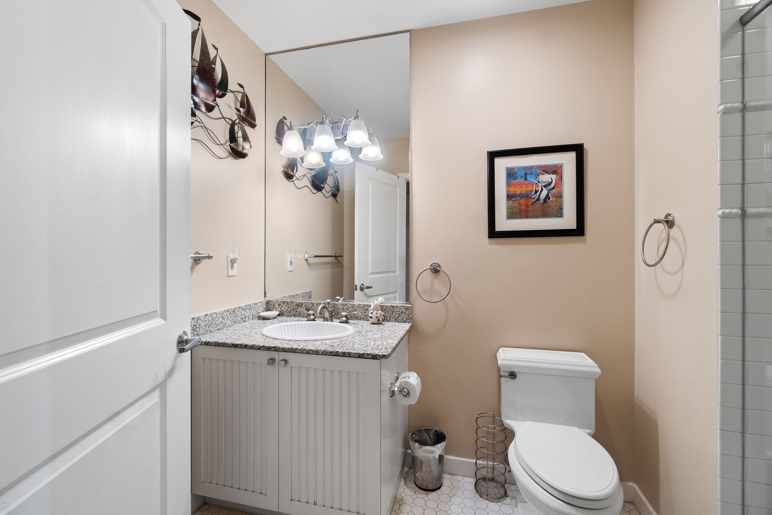 A bathroom with a white sink, a toilet, a mirror, and a shower area.