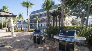 An outdoor patio area with two barbecue grills, a pergola, and palm trees. - Large, True 1 BR, Between Alys & Rosemary (Seacrest)