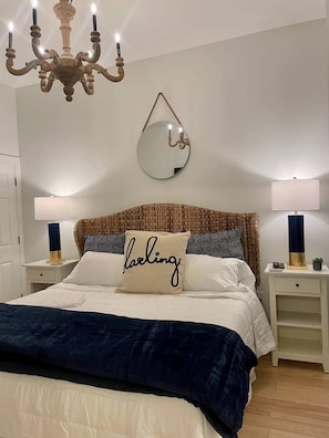 A bedroom with a bed, two bedside tables, a chandelier, a mirror, and a wall-mounted lamp. - Large, True 1 BR, Between Alys & Rosemary (Seacrest)