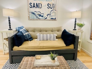 A cozy living room with a sofa, two side tables, a lamp, a potted plant, and a decorative sign. - Large, True 1 BR, Between Alys & Rosemary (Seacrest)