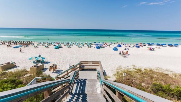 A beach with a wooden boardwalk leading to the shore, featuring numerous umbrellas and beach chairs. - Large, True 1 BR, Between Alys & Rosemary (Seacrest)