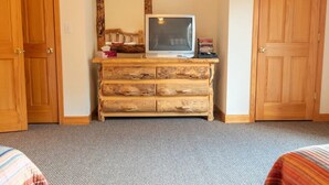 Une pièce comprenant une commode en bois, un téléviseur et un miroir.