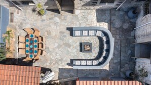 An outdoor patio with a stone floor, a curved seating area, and a built-in barbecue.