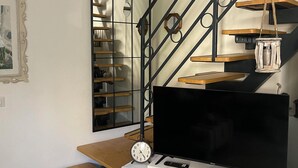 A staircase with a black metal railing, wooden steps, and a white cabinet with a television and a clock. - THE SECRET GARDEN (Forza d'Agrò)