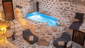 A stone-walled outdoor hot tub area with seating and a wooden door.