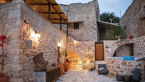 A stone courtyard with a wooden bench, a small table, and a hot tub.