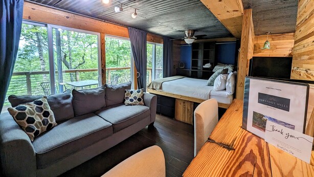 A cozy cabin interior with a sofa, a bed, a desk, and a dining area.