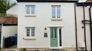 A white two-story house with a green door, numbered 6, and a small sign above the door. - Bridge Hideaway (Llangollen)