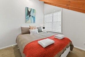 A bedroom with a bed, a window with blinds, a painting on the wall, and a red blanket on the bed. - Peel St | Large Family Home, Walk to CBD (Bathurst)