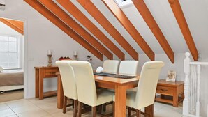 Un comedor con una mesa de madera y sillas, una mesita auxiliar y una chimenea blanca.
