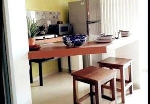 Enjoy casual meals and work sessions in this kitchen with a microwave, bowl, and two stools.