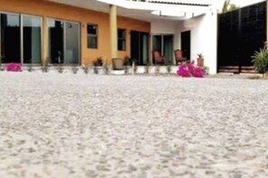 Enjoy the serene atmosphere on the spacious porch, surrounded by lush greenery and a beautiful flowering plant.
