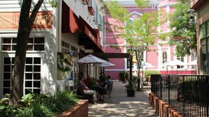 A narrow outdoor corridor with brick planters, a café with outdoor seating, and a red building in the background. - Yoo Hoo! Great Branson resort family value package. 3BD/3BA sleeps 12. (Branson)