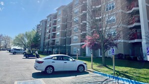 A multi-story residential building with balconies, a parking lot, and a tree with pink blossoms. - Yoo Hoo! Great Branson resort family value package. 3BD/3BA sleeps 12. (Branson)