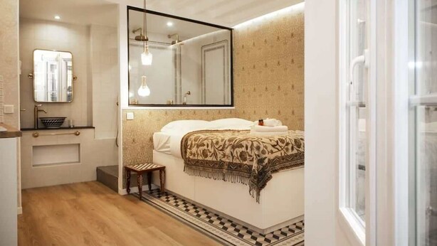 A bedroom with a large bed, a bedside table, a mirror, and a window. - Magnifique appartement familial grand boulevard-6P (Paris)