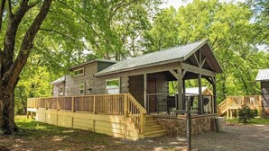 Une cabane dotée d’une véranda, d’une terrasse et d’un mur en pierre.