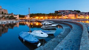 Una marina con barche ormeggiate, un muro in pietra e edifici sullo sfondo.