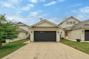 A residential property with a central garage, a driveway, and a well-maintained lawn. - LBJ Lake Lounging-Lakefront w/ Private Heated Pool (Kingsland)