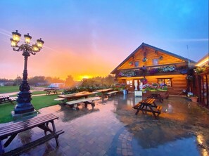 A rustic log cabin with outdoor seating and a fountain, surrounded by a well-maintained lawn and a decorative street lamp. - Beautiful 3 bedroom lodge with hot tub in stunning Northumberland (Morpeth)