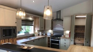 Una cocina moderna con una isla central, electrodomésticos de acero inoxidable, iluminación colgante y armarios empotrados.