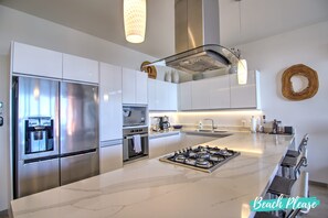 A modern kitchen with a central island, stainless steel appliances, and a built-in oven.