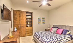Een slaapkamer met een bed, een houten garderobe, een bureau met een vaas en een plafondventilator.
