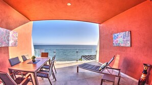 A covered outdoor seating area with a table and chairs, a bench, and a view of the ocean. - CDM 205: Beachfront 2BR w Pool, Gym & Ocean Views (Bucerías)