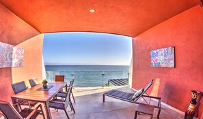 A covered outdoor seating area with a table and chairs, a bench, and a view of the ocean. - CDM 205: Beachfront 2BR w Pool, Gym & Ocean Views (Bucerías)