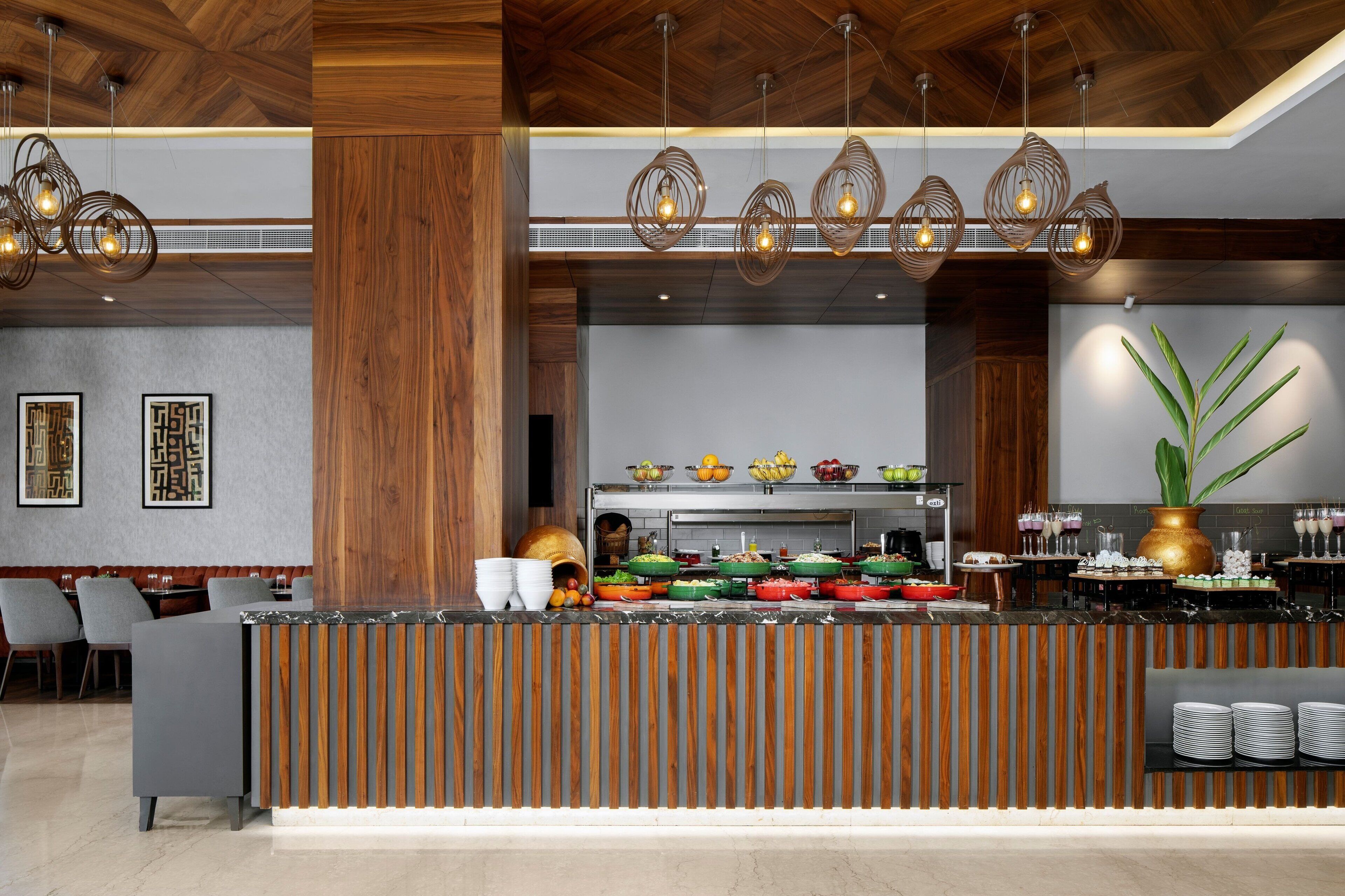 A modern hotel lobby with a reception desk, buffet area, and seating.
