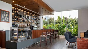 A modern bar area with a counter, shelves with bottles, and a glass display case. There are chairs and a sofa in the seating area. - Four Points by Sheraton Kigali (Kigali)