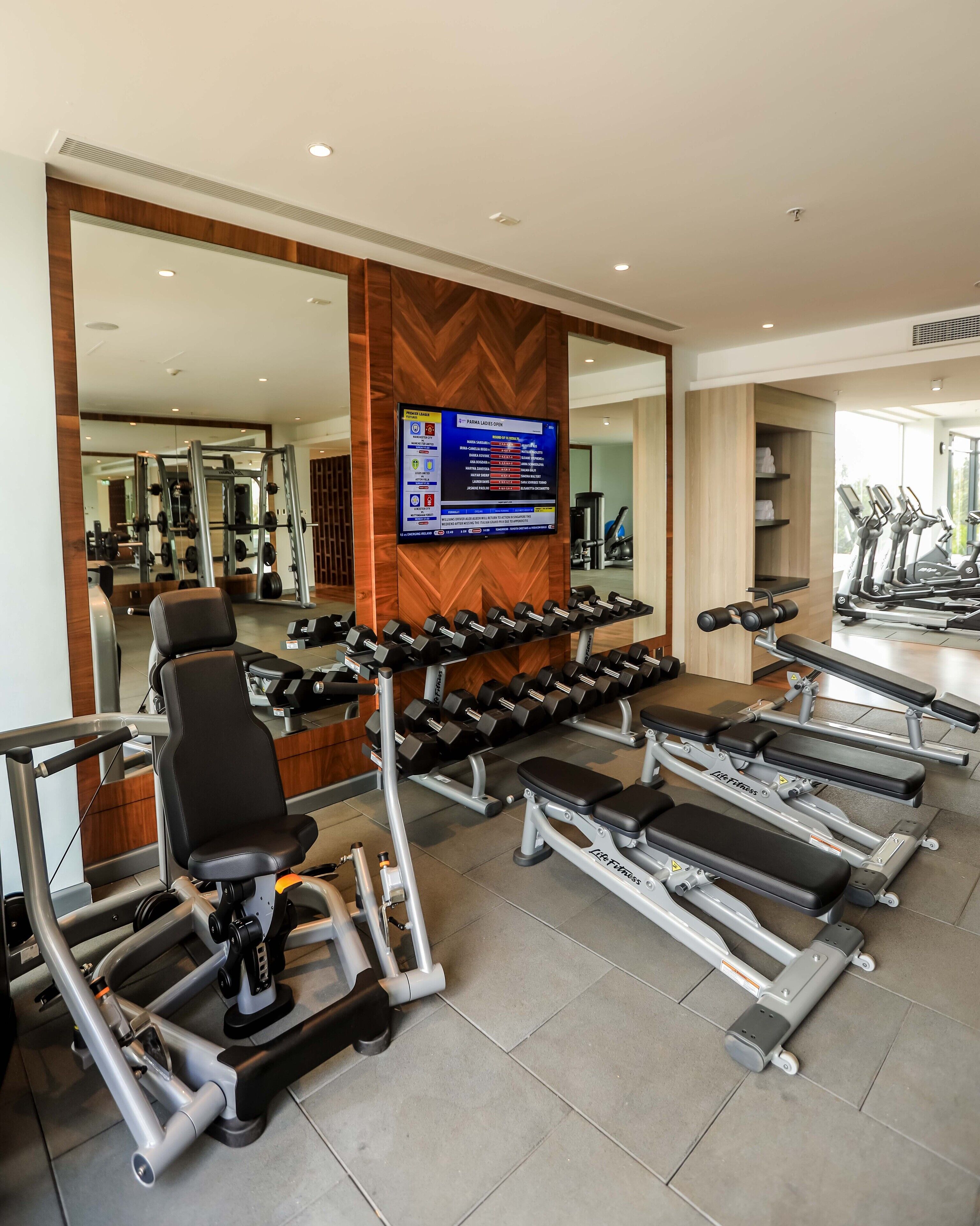 A gym with various exercise equipment, including dumbbells, treadmills, and weight machines.