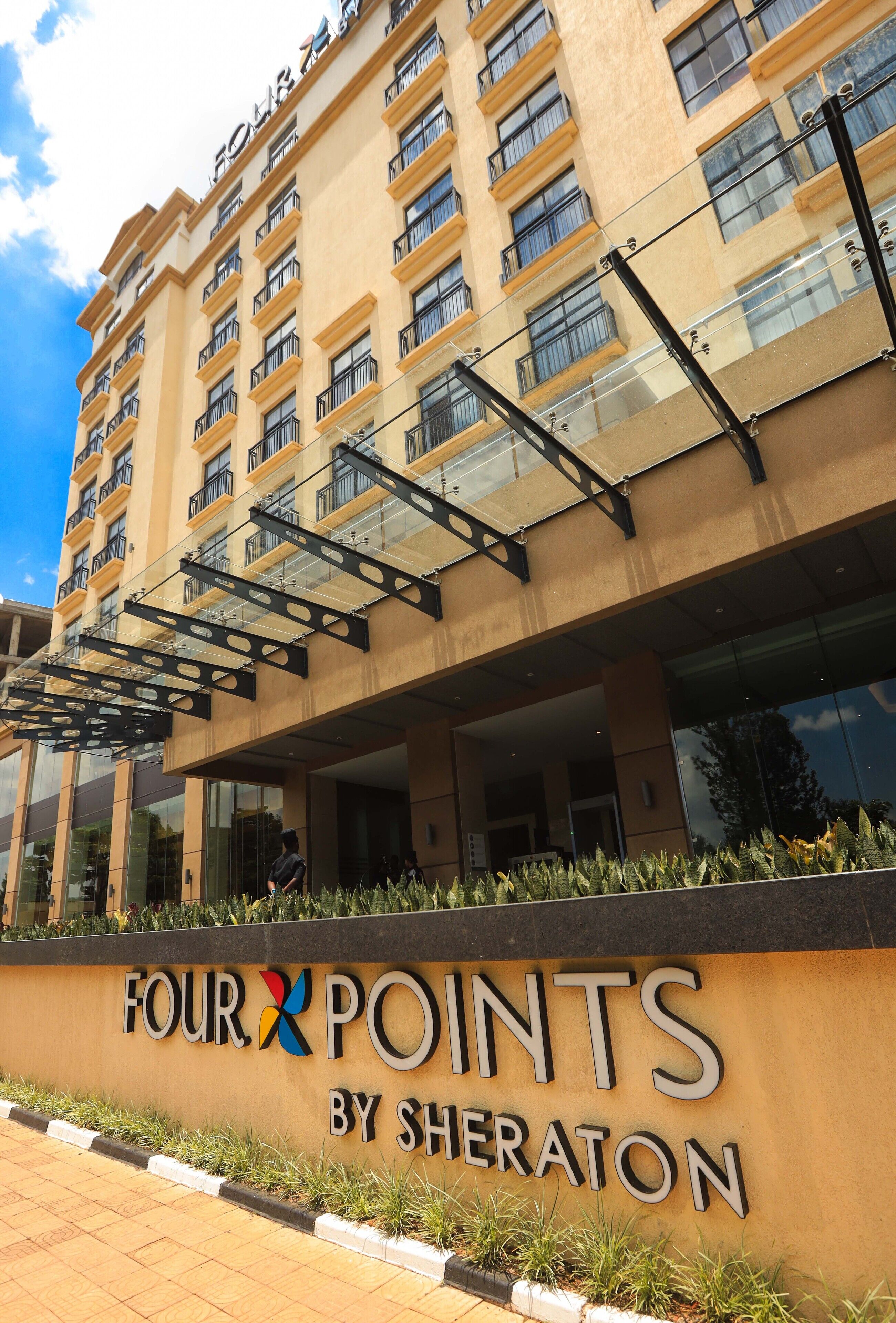 A hotel named "Four Points by Sheraton" with a modern facade, multiple balconies, and a clear sky.