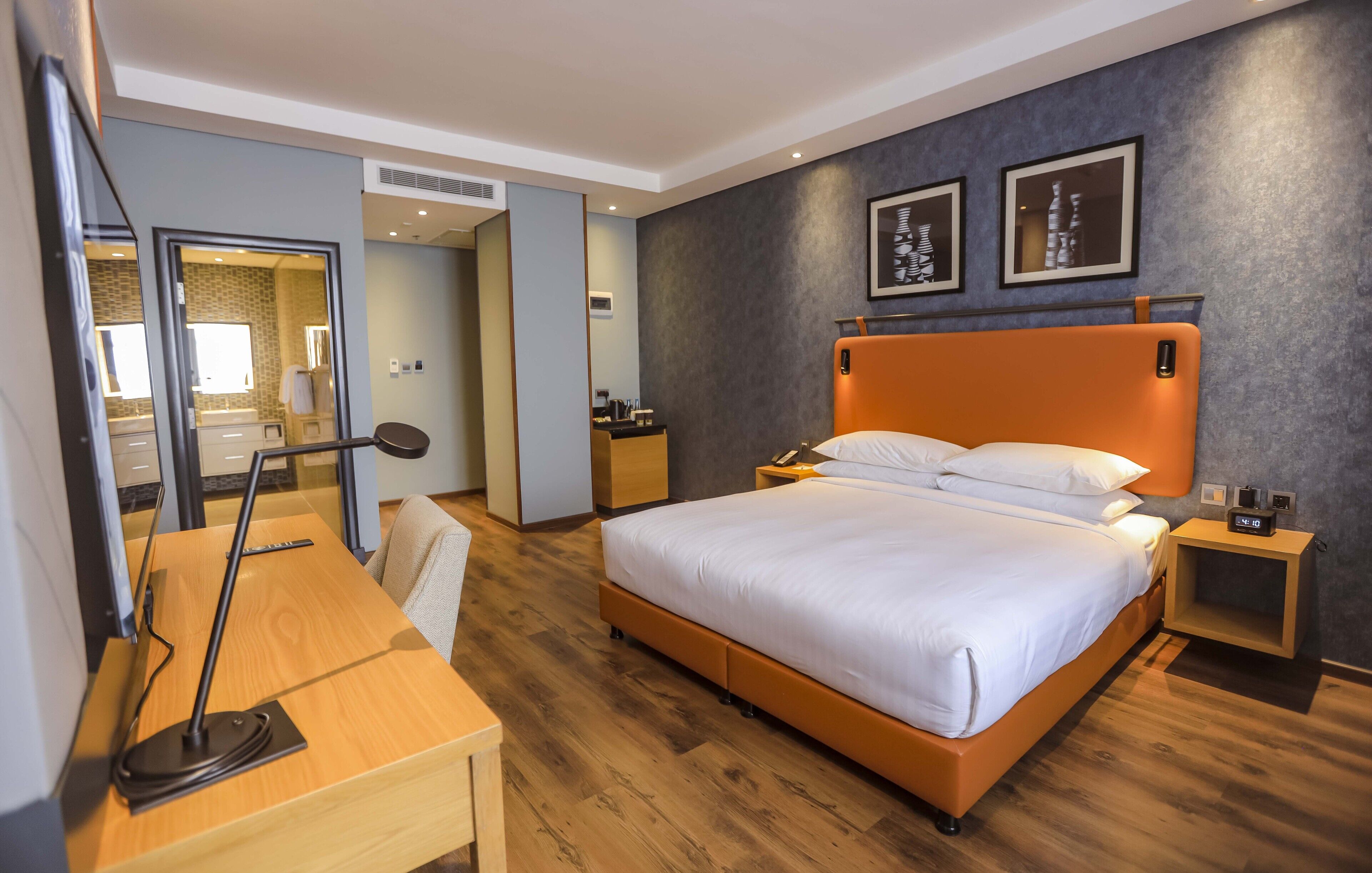 Una habitación de hotel moderna con una cama grande, un escritorio, una silla y una mesita de noche.