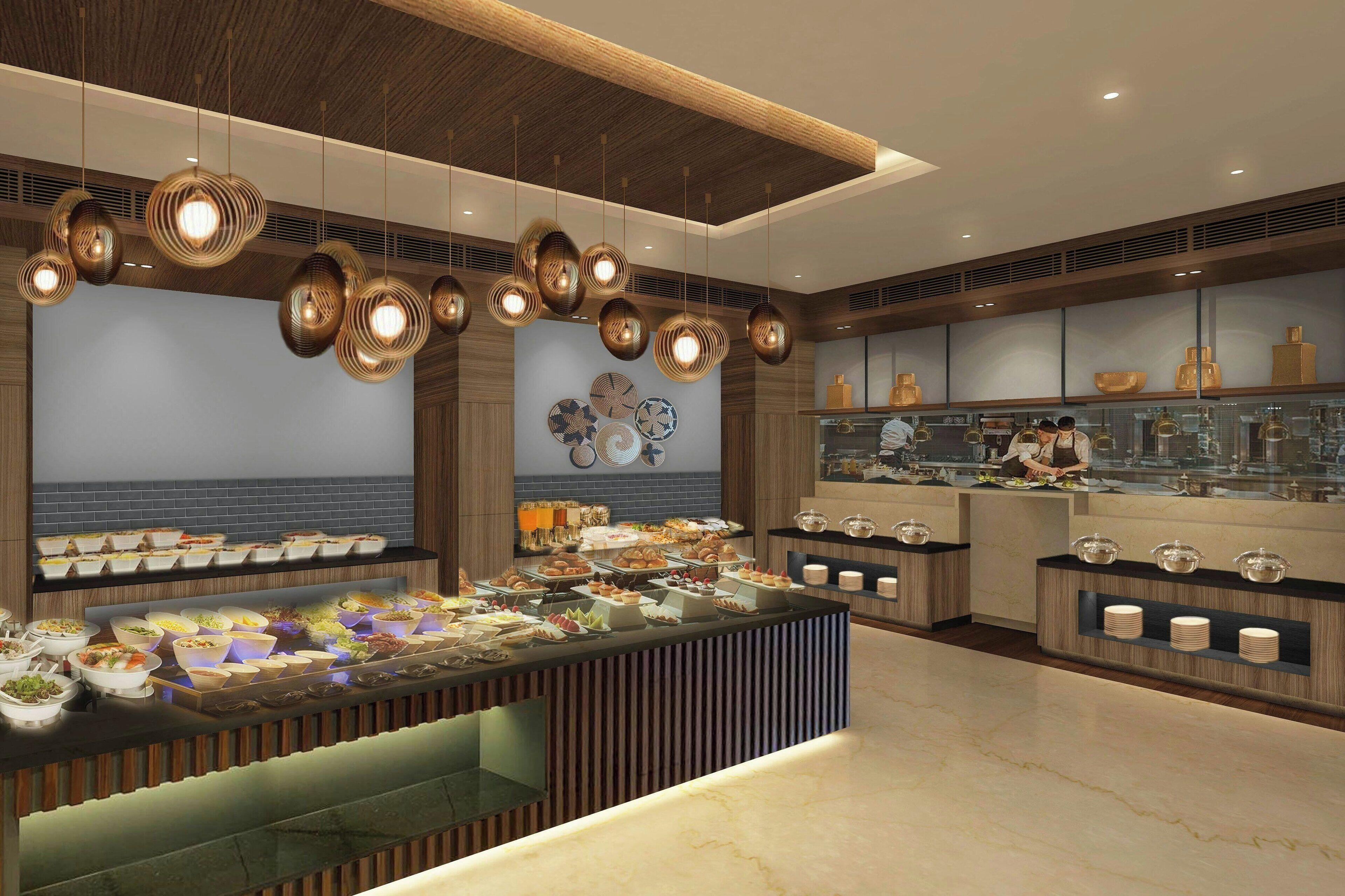Un moderno montaje tipo buffet con múltiples estaciones de comida e iluminación decorativa.