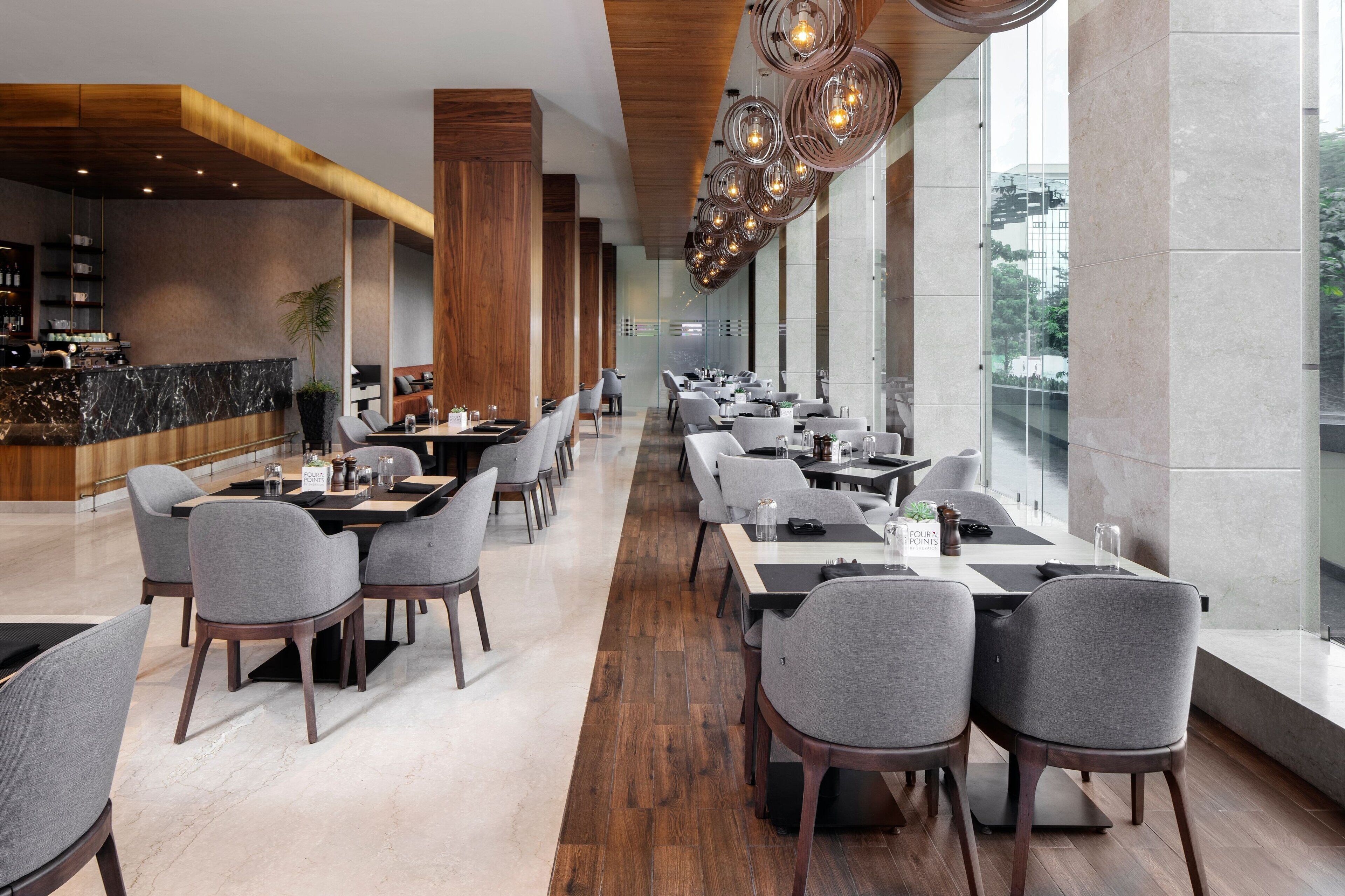 Un restaurante moderno con techos altos, detalles de madera y una amplia zona de comedor con mesas y sillas.