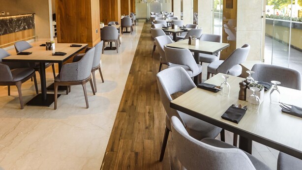 A modern restaurant with wooden ceiling beams, long tables, and grey chairs. - Four Points by Sheraton Kigali (Kigali)