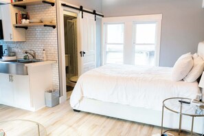 A bedroom with a large bed, a bedside table, and a window. - Modern Carriage House | Prime Location • Parking (Indianapolis)