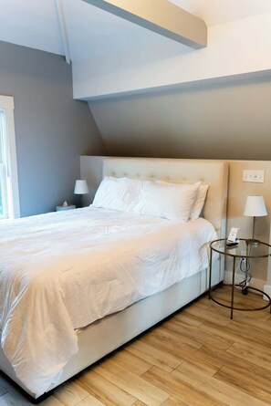 A modern bedroom with a large bed, bedside lamps, and a small table with a phone.