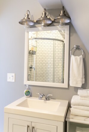 A bathroom with a white sink, a mirror, and a towel rack. - Modern Carriage House | Prime Location • Parking (Indianapolis)