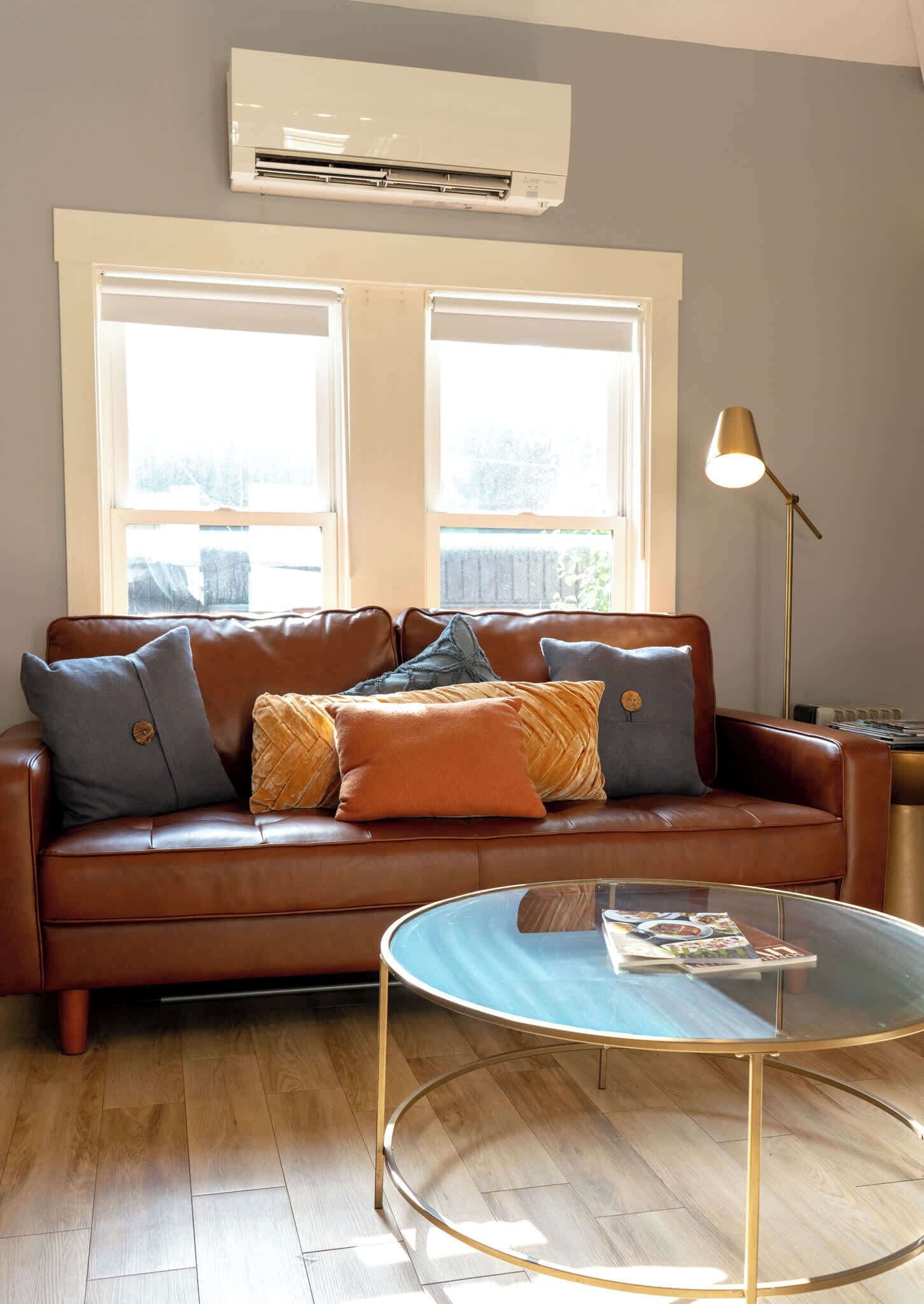 A living room with a brown leather sofa, a glass coffee table, and a floor lamp.