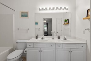 Ein modernes Badezimmer mit einem weißen Waschbecken, zwei Spiegeln und einer Toilette.