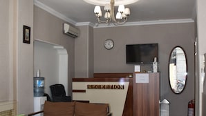 A reception area with a reception desk, a clock, a television, and a mirror. - Taksim Palace Hotel Apart  (Istanbul)