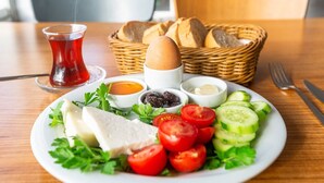 A plate of food with bread, eggs, and vegetables, and a glass of red drink on a wooden table. - Taksim Palace Hotel Apart  (Istanbul)