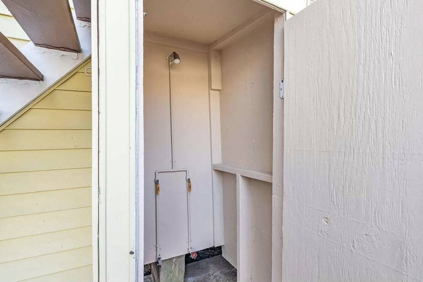 Un espace étroit et fermé, doté d’une porte et d’un luminaire au plafond.