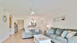 A living room with two sofas, a coffee table, a ceiling fan, and a chandelier. - Amazing 2 bedroom unit located on golf course near Siesta Key Beaches (Sarasota)