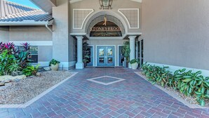 A hotel entrance with a brick pathway leading to double doors, a sign above the doors, and potted plants on either side. - Amazing 2 bedroom unit located on golf course near Siesta Key Beaches (Sarasota)