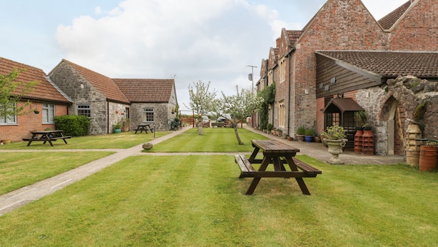A courtyard with picnic tables, stone buildings, and a clear sky.