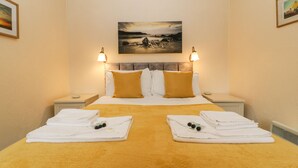A hotel room with a large bed, two nightstands, a painting above the bed, and towels on the bed.